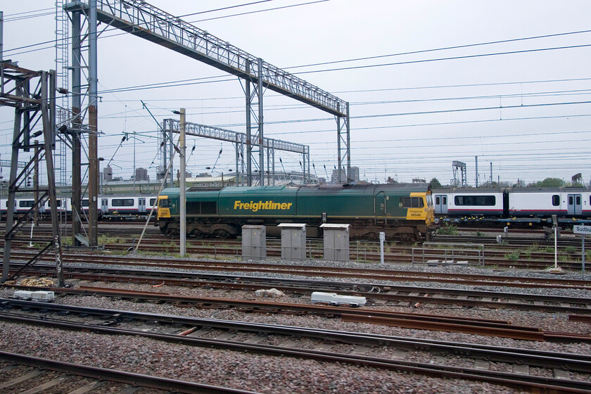 66546, stabled, Wembley Yard 
 Stabled between duties, 66546 is seen as we pass Wembley yard. Having been a fixture for months now, a line of 'warm' stored and debranded former Greater Anglia Class 321s stand in the background facing a very uncertain future. 
 Keywords: 66546 stabled Wembley Yard Freightliner