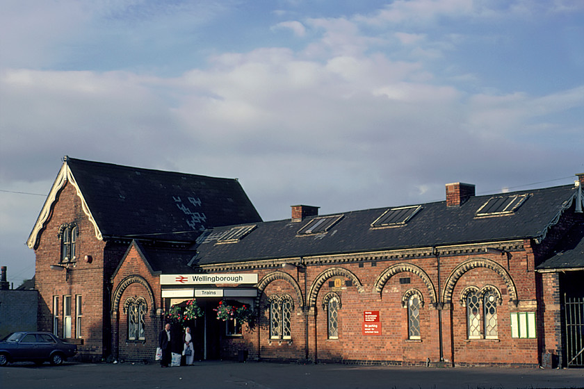 Frontage, Wellingborough Station 
 The frontage of Wellingborough station looks smart in the evening sunshine making the red brickwork look particularly 'warm'. Apart from one or two cosmetic changes, the appearance of the station changed very little until more recent years with much work taking place to prepare for electrification. In addition, a new road has been constructed in front of it (Driver Way) linking to a vast new housing development at Stanton Cross. The Midland Railway commissioned the esteemed architect C. H. Driver (hence the name of the new road just mentioned) to design the station that was opened in 1857. It is Grade II listed noted for its distinctive 'Venetian Gothic style'. 
 Keywords: Frontage Wellingborough Station