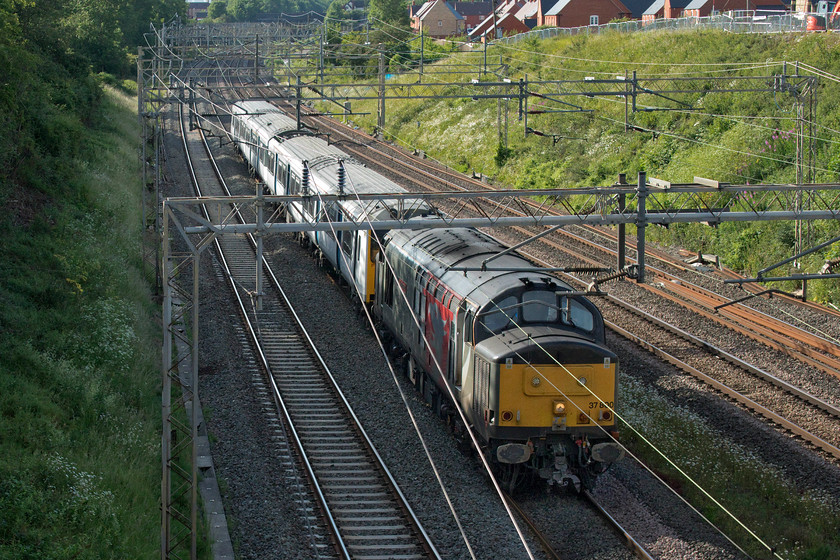 37800 & 317340, 11.30 Kilmarnock Bonnyton-Ilford EMUD (5Q50, 6E), Ashton Road bridge 
 Not the ideal location and not the one that I was going to use for this particular working however control switched the 11.10 Kilmarnock to Ilford 5Q50 unit drag on to the fast line via Weedon after it shot through Rugby without stopping! This left me short of time so I had to dash across the field from home, breaking briefly into a run, in order to get to Ashton Road bridge. Terribly backlit 37800 'Cassiopeia' drags 317340 back to Ilford after receiving attention at Brodie Engineering in Kilmarnock. Coincidentally, I saw the same unit heading north on its outward journey from the other side of the bridge three weeks earlier also being towed by 37800, see.... https://www.ontheupfast.com/p/21936chg/29061996604/x37800-317340-16-16-ilford-emud-kilmarnock 
 Keywords: 37800 317340 11.30 Kilmarnock Bonnyton-Ilford EMUD 5Q50 Ashton Road bridge Cassiopeia Rail Operations Group ROG Europheonix GA Greater Anglia