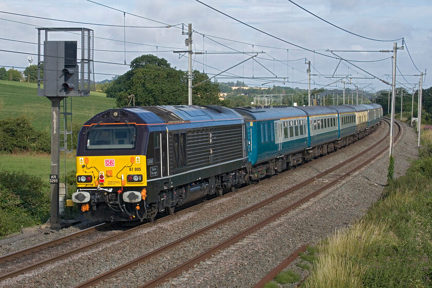 67005, 07.29 London Euston-Carlisle (1Z85, 2E), Milton crossing 
 67005 'Queens' Messenger' brings up the rear of the DB Schenker private charter as it passes Milton crossing between Roade and Blisworth. This 1Z85 charter would go to Carlisle via the Settle and Carlisle route but I am unsure as to what would haul the train over this leg of its journey. This charter had aroused a surprising amount of local interest with no fewer than three other photographers at this spot! 
 Keywords: 67005 07.29 London Euston-Carlisle 1Z85 Milton crossing Queens' Messenger