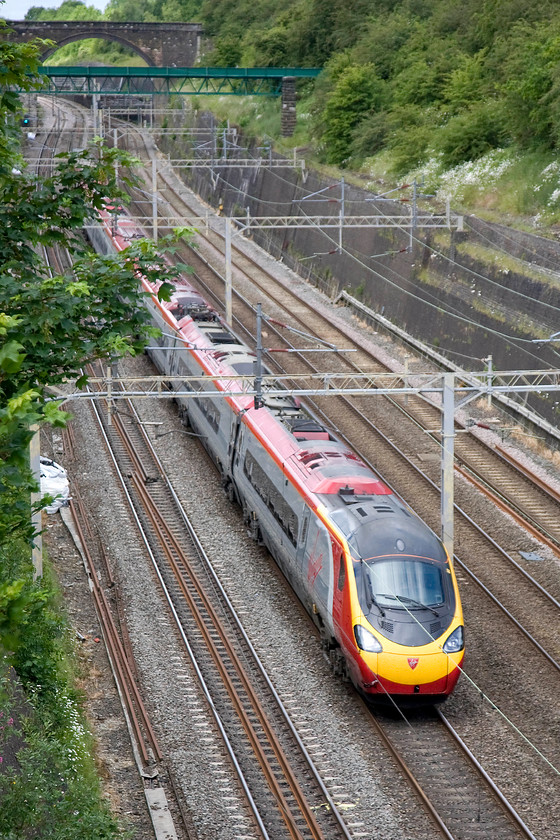 Class 390, VT 09.38 Glasgow Central-London Euston (1M05), Roade cutting 
 An unidentified class 390 weaves its way through Roade cutting with the 09.38 Glasgow to Euston 1M05 working. The stone bridge in the background is locally referred to as Accommodation or Thorpe Wood Bridge and is a remote spot crossed by a footpath. The green structure in the middle distance is an aqueduct carrying a stream across the cutting that has recently undergone extensive repairs and painting by Network Rail due to it being more like a colander than an aqueduct! 
 Keywords: Class 390 09.38 Glasgow Central-London Euston 1M05 Roade cutting Virgin Trains Pendolino