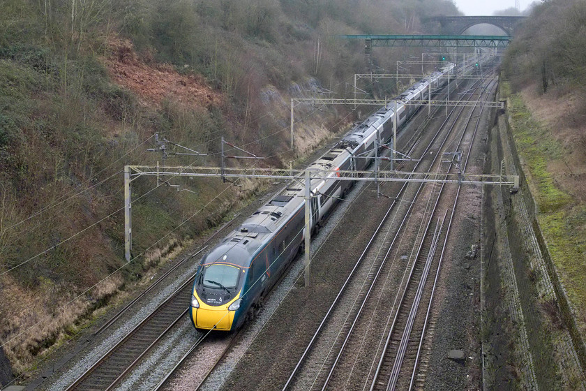 390155, VT 11.35 Manchester Piccadilly-London Euston (1A29, RT), Roade cutting 
 With planning consent recently granted for the development of a huge strategic rail freight interchange to be named Northampton Gateway a short distance from this location above Roade cutting, this scene will be dramatically changed in the coming couple of years. As part of the awarding of planning consent the developers of the site, Roxhill, are bound to construct a bypass for Roade village. This will cross the cutting diagonally in this view halfway between where I am standing and the green aqueduct. As a villager, I welcome the bypass but at what price? 390155 passes through the cutting forming the 11.35 Manchester to Euston service. 
 Keywords: 390155 11.35 Manchester Piccadilly-London Euston 1A29 Roade cutting Pendolino Avanti West Coast