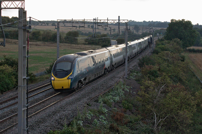 390114, VT 16.47 Liverpool Lime Street-London Euston (1A54, 1E), Blisworth 
 Catching a little of the setting sun as it passes Blisworth in Northamptonshire 390114 'City of Manchester' works the 16.47 Liverpool Lime Street to Euston service. Soon it will rejoin the line that by-passes Northampton and run into London on the eponymous up fast quadruple layout as a marked contrast to the winding and curving twin track old route seen here. 
 Keywords: 390114 16.47 Liverpool Lime Street-London Euston 1A54 City of Manchester Blisworth