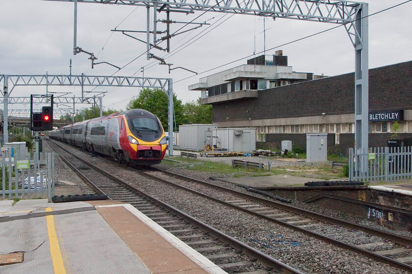 Class 390, VT 13.00 London Euston-Manchester Piccadilly, Bletchley station 
 Passing the recently closed Bletchley PSB at line speed, an unidentified Class 390 heads north with the Virgin 13.00 Euston to Manchester service. The box, despite closing on 31.12.12, was open today for visitors to admire its brutalist 1960s interior and low-tech electronics! 
 Keywords: Class 390 13.00 London Euston-Manchester Piccadilly Bletchley station Virgin Pendolino