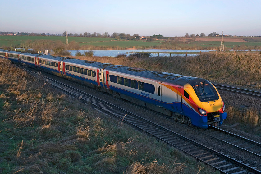 222001, EM 07.29 Sheffield-London St. Pancras (1C20), Irchester Junction SP922673 
 Pioneer Meridian 222001 'The Entrepreneur Express' begins the climb from the Nene Valley, seen in the background, to Sharnbrook summit working the 07.29 Sheffield to St. Pancras service. During winter and periods of heavy rain, the Nene Valley often floods creating the huge natural lakes that in turn become a haven for wildlife. This natural process of the floodplain doing what it is naturally designed to do prevents flooding elsewhere causing problems unless the planners have permitted development in these areas! 
 Keywords: 222001 07.29 Sheffield-London St. Pancras 1C20 Irchester Junction SP922673 EMT East Midlands Trains The Entrepreneur Express