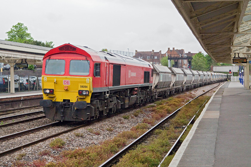 59204, 13.30 Whatley Quarry-Dagenham Dock (6L21), Newbury station 
 59204 is one of the later batch of class 59s that arrived in the UK in 1995. It looks very smart in ti new DB Schenker livery red livery and branding as it passes Newbury station with the 13.30 Whatley Quarry to Dagenham Docks 6L92 stone train. Despite their age, the design of these American built locomotives have stood up to scrutiny with them remaining reliable and fit for purpose representing a good investment for their original buyers. 
 Keywords: 59204 13.30 Whatley Quarry-Dagenham Dock 6L21 Newbury station