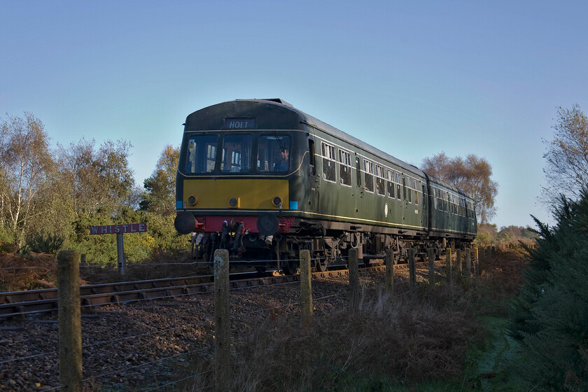 M51192 & M56352, 09.45 Sheringham-Holt, Kelling Heath TG100412 
 Under an intense blue autumn sky, the first service of the day on the North Norfolk Railway crosses Kelling Heath. A Class 101 DMU made up of cars M51192 and M56352 works the 09.45 Sheringham to Holt service seen passing a nice reproduction whistle sign warning people around a popular and busy footpath crossing just near to the tall trees to the right of the photograph. 
 Keywords: M51192 M56352 09.45 Sheringham-Holt Kelling Heath TG100412 Class 101 DMU