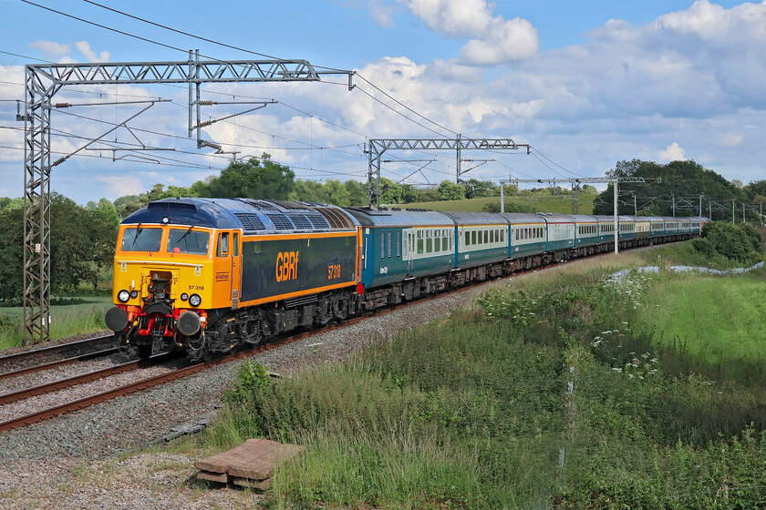 57310, 16.08 Wembley Yard-Burton Ot Wetmore (5Z63, RT), Milton Crossing 
 Returning a set of stock used on a charter the previous day would not normally attract the attention of many photographers but no fewer than five turned up at this location a short distance north of Roade cutting at Milton crossing. The reason was the motive power being used, namely GBRf's newly repainted 57310. The superb paint job was completed by Loughborough Works during April and I think that it suits the the former Virgin Thunderbird very well. With matching 47306 at the rear the train was running as 5Z63, the 16.08 Wembley Yard to Burton-ot-Wetmore 
 Keywords: 57310 16.08 Wembley Yard-Burton Ot Wetmore 5Z63 Milton Crossing