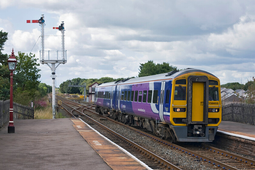 158855, NT 15.05 Carlisle-Leeds (1E23), Appleby station 
 158855 arrives at Appleby station working Northern's 15.05 Carlisle to Leeds service. It is passing the impressive down home bracket signal that has two very tall dolls. The taller doll holds the down starter with the submissive one holding the shunting signal that permits access to the sidings owned by the Appleby Heritage Centre. 
 Keywords: 158855 15.05 Carlisle-Leeds 1E23 Appleby station Northern