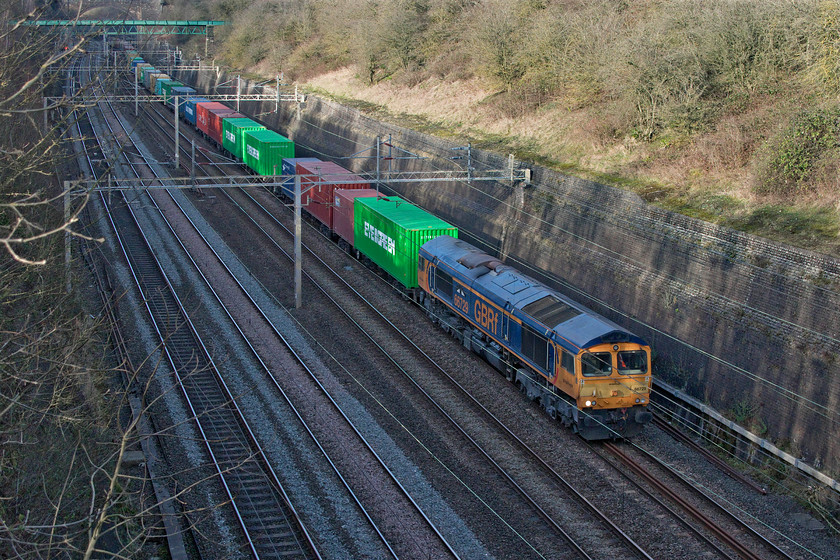 66729, 13.07 Hams Hall-Felixstowe South (4L20, 30E), Roade cutting 
 66729 'Derby County' makes its way very slowly through Roade cutting leading the 13.07 Hams Hall to Felixstowe Freightliner service. It really was going very slowly - I would estimate about 30mph as the train was very lengthy and heavily loaded with only a few empty flats. The sun is just illuminating the front and side of the train with the rest of the cutting in deep winter shadow. Photoshop has done a good job at balancing things out a little. 
 Keywords: 66729 13.07 Hams Hall-Felixstowe South 4L20 Roade cutting Freightliner Derby County