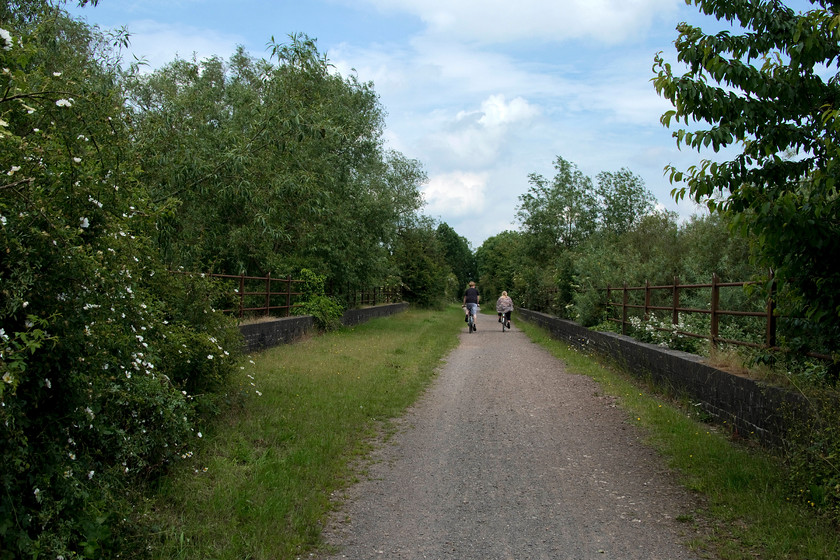 Former trackbed & bridge 16, Brampton Valley Way 
 My wife and son ride their bikes across bridge 16 on the Brampton Valley way on the approach to the Brixworth to Spratton crossing. This line was a double track that ran from just north of Northampton at Kingsthorpe to link with the Midland line at Market Harborough. Its fortunes waxed and waned over the years with a number of closure and reopenings with it finally succumbing in 1981. Today, it would prove to be a very useful relief line, particularly for freight with the dearth of east-west lines that exist. 
 Keywords: Former trackbed bridge 16 Brampton Valley Way