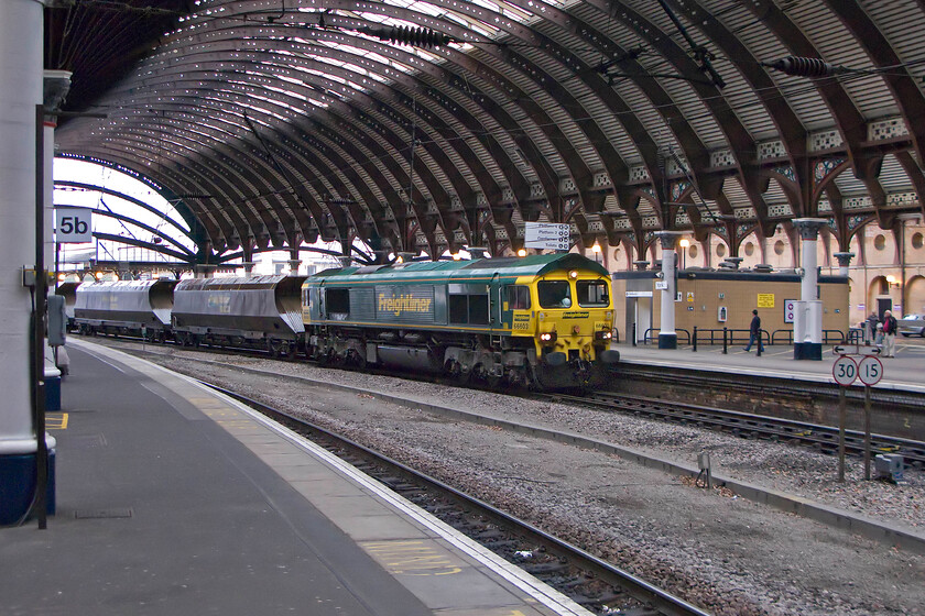 66603, up coal train, York station 
 Coming in from the pouring rain, 66603 leads an up bulk working probably containing coal through York station. Unfortunately, despite all the technology available I was unable to identify this working so if anybody with local knowledge can help out that would be useful! 66603 has led an anonymous life since its arrival in the UK nearly fourteen years ago in November 2000. It has worn its Freightliner livery ever since and has never been named. 
 Keywords: 66603 up coal train York station