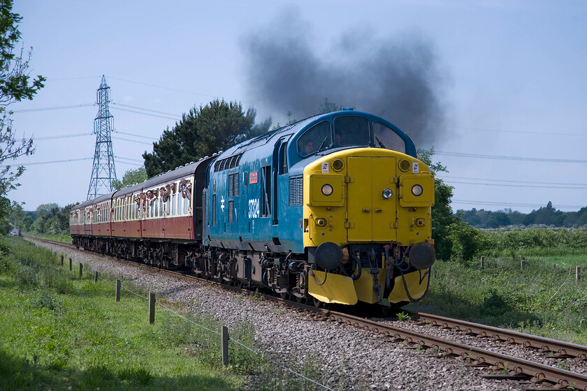 37324 (37099), 13.52 Yarwell Junction-Peterborough NV (2E51), Ailsworth TL109979 
 An identity crisis? The 13.52 Yarwell to Peterborough Nene Valley service creates quite an exhaust show as it accelerates away from Wansford towards Ailsworth Lane crossing. As 37324 'Clydebridge' operated on the Scottish Region from 1986 after being numbered 37099 from the introduction of TOPS. In preservation, it still wears the hallmarks of being a Scottish Region locomotive with its mini headlight and snowploughs. However, its flanks are not adorned with the trademark Scottie dogs that seems to be an unusual ommition? 
 Keywords: 37324 37099 13.52 Yarwell Junction-Peterborough Nene Valley 2E51 Ailsworth TL109979 Clydebridge