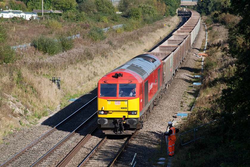 60039, 13.30 Appleford-Whatley (6C48), Hay Lane bridge SU108824 
 60039 'Dove Holes' accelerates past a track worker at the head of the 13.30 Appleford to Whatley empty stone wagons. This 6C48 will continue its way along the GWML past Chippenham to then take the Melksham line at Thingley Junction to continue to Westbury and then to Whatley near Frome. The train is passing the busy B4005 Hay Lane bridge just west of Swindon with the M4 over-bridge just seen at the top of the picture. 
 Keywords: 60039 13.30 Appleford-Whatley 6C48 Hay Lane bridge SU108824