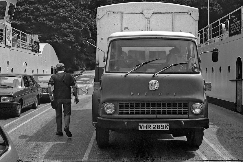 On-board, King Harry Ferry 
 The King Harry Ferry is almost loaded and ready to sail the short distance across the River Fal at Trelissick. The drivers of the motley collection of vehicles will be grateful that the ferry is running as it saves a long and slow alternative journey of twenty-eight miles via Truro. The smoking and newspaper-reading driver of the Bedford TK will face quite a challenge when he disembarks the ferry with a very steep climb from the estuary requiring every bit of his truck's meagre 72bhp! The Morris Ital next to the truck will not do much better one suspects! 
 Keywords: On-board King Harry Ferry