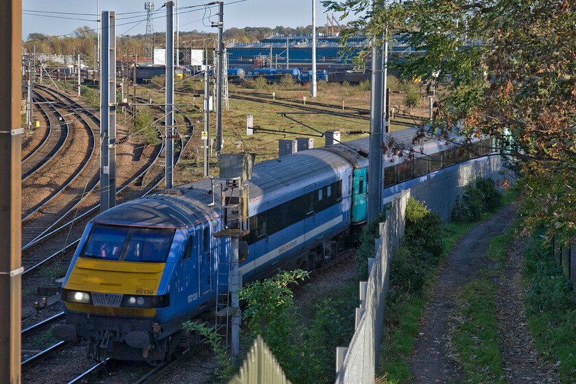 82139, LE 12.30 London Liverpool Street-Norwich (1P28) & 57011, 15.08 Norwich Crown Point-Stowmarket RHTT (3S01), Thorpe Junction 
 Unfortunately, the sun is a little low in the autumn sky to illuminate the main subject of the photograph taken from Norwich's Canary Way bridge. DVT 82139 leads the 12.30 from Liverpool Street on its final approach to Norwich about to cross Thorpe Junction. In the background, one of the season's RHTT trains waits on the chord in front of Crown Point depot with DRS' 57011 at the head. 
 Keywords: 82139 12.30 London Liverpool Street-Norwich 1P28 57011 15.08 Norwich Crown Point-Stowmarket RHTT 3S01 Thorpe Junction Greater Anglia