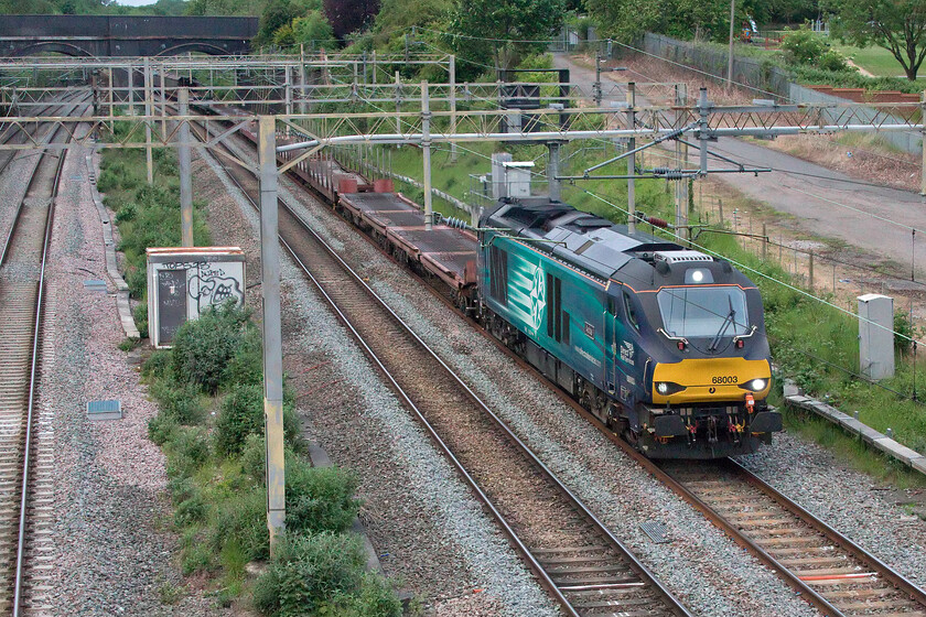 68003, 15.49 Garston Car Terminal-Dagenham Docks (6L48, 7E), site of Roade station 
 In very poor lighting 68003 'Astute' leads the daily 6L48 15.49 Garston to Dagenham Docks empty car transporter service. The train is seen on the up slow line passing the site of Roade station with the A508 overbridge seen to the top left. Whilst this service is normally electric hauled by a Class 88 on this occasion diesel traction was utilised and I certainly knew it hearing the locomotive for some time prior to its passing before it even entered Roade cutting some mile or so away! 
 Keywords: 68003 15.49 Garston Car Terminal-Dagenham Docks 6L48 site of Roade station Astute