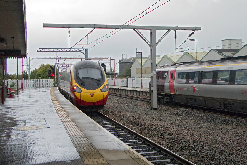 Class 390, VT 10.15 Manchester Piccadilly-London Euston (1A24) & Class 220, XC 06.37 Bournemouth-Manchester Piccadilly (1M26), Stoke-on-Trent station 
 At the southern end of Stoke-on-Trent station, an unidentified Class 390 Pendolino leaves working the 10.15 Manchester to Euston service whilst a Class 220 Voyager arrives with the 06.37 Bournemouth to Manchester train. This view clearly shows the wide gap between the up and down lines that until relatively recently had a relief 'through' track that was removed in 2009, a retrograde step I wonder? 
 Keywords: Class 390 10.15 Manchester Piccadilly-London Euston 1A24 Class 220 06.37 Bournemouth-Manchester Piccadilly 1M26 Stoke-on-Trent station CrossCountry Voyager Virgin Pendolino