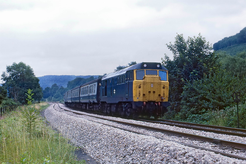 31412, unidentified up working, Limpley Stoke 
 Another local class 31 heads along the Avon Valley with a Portsmouth Harbour working that would have originated at either Bristol Temple Meads or Cardiff Central. The train is hauled by 31412 and is approaching Limpley Stoke taken on a section of line that was three-track wide until the third was removed when the Camerton branch was closed in the 1950s. This branch and section of line were used for the filming of the Titfield Thunderbolt film of 1953. Down below and to the left of the fence is the B3108 road so I am not at all sure as to how I got to this position to take the picture, and to be honest, I don't want to remember! 
 Keywords: 31412 up working Limpley Stoke