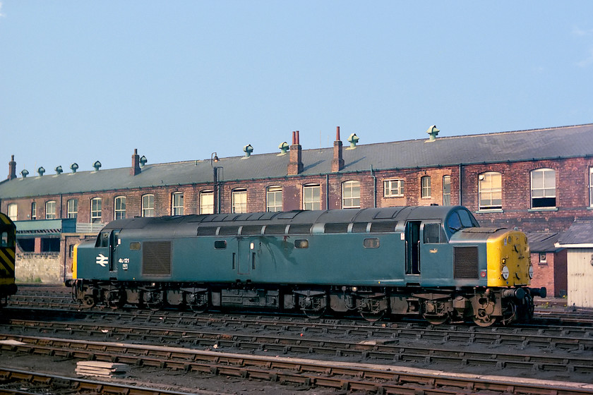 40121, stabled, Doncaster Works 
 40121 stands outside Doncaster Works taken from the platform of the station. This side-on pictures shows the bulk of these heavy type 4s clearly with their 1Co-Co1 wheel arrangement the bogies of which proved so fateful in the classes later lives. A view like this can still be taken today but the subjects of the image will be somewhat different to a 40! 
 Keywords: 40121 stabled Doncaster Works