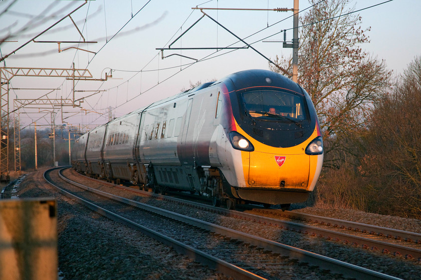 390020, VT 07.05 Wolverhampton-London Euston (1B05, 3L), Bugbrooke footbridge 
 390020 (I think!) passes Bugbrooke in Northamptonshire working the 07.05 Wolverhampton to Euston. The early morning sun had just raised itself above the hill behind me enough to illuminate the front end of the Pendolino, but my goodness, it remained bitterly cold! 
 Keywords: 390020 07.05 Wolverhampton-London Euston 1B05 Bugbrooke footbridge