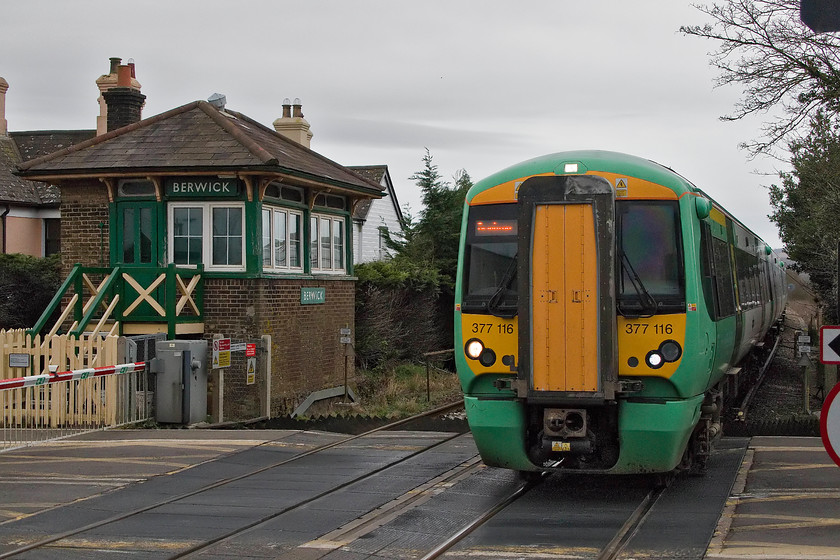 377116, SN 14.18 Ore-Brighton (1F49, RT), Berwick station 
 377116 passes Berwick level crossing at speed with the 14.18 Ore to Brighton train. It is testament to the technology in a modern camera such as the canon GX1 Mk.IV that a fast shutter speed can be used in such dull conditions and still produce a reasonably noise-free result with very good tonal range. The last time that I photographed this unit was at Billingshurst in April 2013, see..... https://www.ontheupfast.com/p/21936chg/30053859246/x377116-unidentified-up-working-billingshurst 
 Keywords: 377116 14.18 Ore-Brighton 1F49 Berwick station