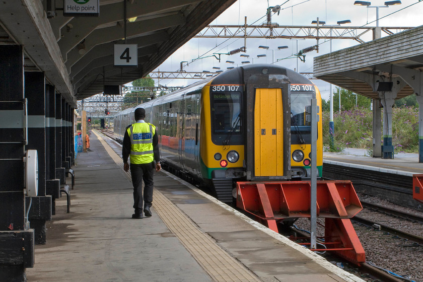 350107, LM 09.21 Northampton-Rugby ecs (5U22), Northampton station 
 350107 waits in Northampton's bay platform four to leave with the 09.21 to Rugby empty coaching stock working. The security operative walking up the length of the platform spends his day, from what I can see, doing this. I wonder what his daily steps are recorded on his 'phone in his pocket? 
 Keywords: 350107 09.21 Northampton-Rugby ecs 5U22 Northampton station London Midland Desiro