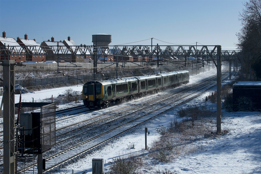 350242, LN 10.15 London Euston-Birmingham New Street (1Y11, 7L), site of Roade station 
 Kicking up a cloud of snow behind it, 350242 passes the site of Roade station working the 10.15 Euston to Birmingham New Street service. Whilst weather such as this affords opportunities that are rarely available, the images recorded by the camera often need a considerable amount of post-processing. The first issue is that the camera often struggles in 'automatic' mode to get things right by underexposing due to the preponderance of bright snow. Secondly, in automatic white balance mode it often goes to the cool end of the spectrum creating a blue hue, particularly in the shadows. 
 Keywords: 350242 10.15 London Euston-Birmingham New Street 1Y11 site of Roade station London Northwestern Desiro