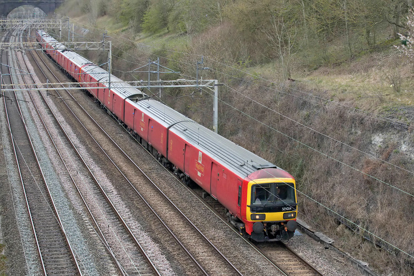 325014, 11.20 Crewe TMD-Willesden (5A91), Roade cutting, Hyde Road bridge 
 Following regular maintenance at Crewe International Electric Maintenance Depot (Crewe IEMD) there is a Fo path on the busy WCML's timetable allowing a DB operated Class 325 to return to its operational base the Princess Royal Distribution Centre (PRDC) between Wembley and Willesden. Passing Roade's Hyde Road bridge 325015 leads two other units as the 5A91 Crewe to Willesden working. Contrary to what many believe these units are not based on the highly successful Networker units despite sharing the same nosecone design. They are, in fact, a Class 319 from top to bottom meaning that they have proved to be reliable units since their introduction in 1995. 
 Keywords: 325014 11.20 Crewe TMD-Willesden 5A91 Roade cutting Hyde Road bridge Royal Mail Networker Class 319