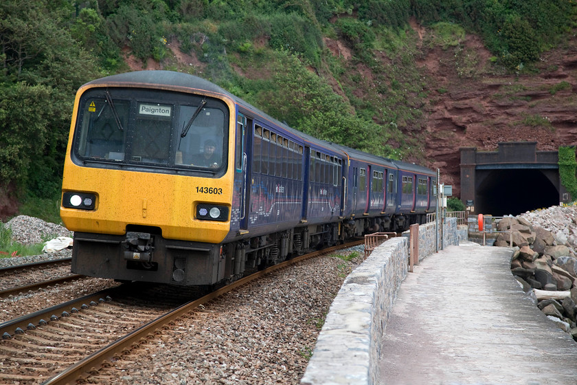 143603, GW 14.24 Exmouth-Paignton (2T19, 1L), Parsons Tunnel 
 142603 and a class 150 has just emerged from Parsons Tunnel on the sea wall in south Devon. It is working the 14.24 Exmouth to Paignton service. I find it a constant surprise that Network Rail have yet to install the dreaded palisade fencing along the top of the wall. The lengths that they go to in some locations that are far less vulnerable that this, for example the WCML around Shap, when compared to this stretch seems to make no sense. I would love to have a look at their risk assessment! Mind you, I am not complaining, and long may it stay like this for all to enjoy. 
 Keywords: 143603 2T19 Parsons Tunnel