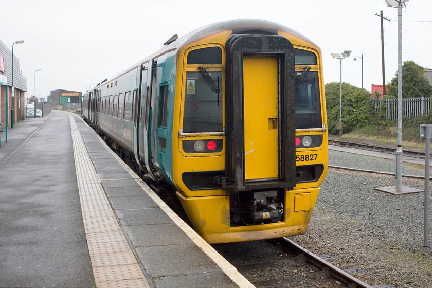 158827, AW 13.38 Pwllheli-Machynlleth & Birmingham International (2G55 & 1G55), Pwllheli station 
 At a dismal Pwllheli station 158827 is about to leave forming the 13.38 to Birmingham International. This train will join with a service from Aberystwyth at Machynlleth and work forward as the 1G55. Pwllheli station is now a signal platform affair that is a shadow of its former self. Part of the original station building still remains being incorporated into a small retail development and travel centre. 
 Keywords: 158827 13.38 Pwllheli-Machynlleth Birmingham International 2G55 1G55 Pwllheli station