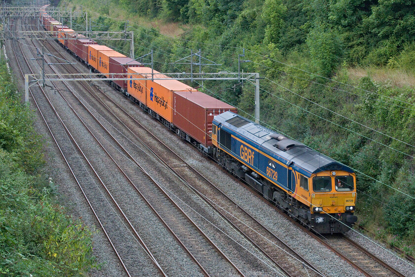 66729, 13.57 Birch Coppice-London Gateway (4L68, 4L), Hyde Road bridge 
 The heavily loaded 4L68 13.57 Birch Coppice to London Gateway passes slowly through Roade cutting lead by 66729 'Derby County'. From a standing start in Northampton, it is a steady and long climb to this point passing the village of Roade that shows the limitations of a Class 66 especially when compared with an electrically hauled service that makes much lighter work of things! 
 Keywords: 66729 13.57 Birch Coppice-London Gateway 4L68 Hyde Road bridge Derby County GBRf