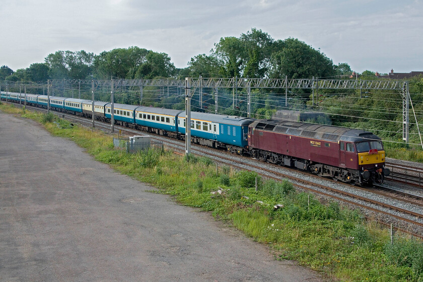 47826, outward leg of 'The Well-Dressed Queen and the Buxton Bush', 06.48 London Euston-Buxton (1Z86, 26L), site of Roade station 
 Unfortunately, I cocked up the framing of this photograph at Roade showing 47826 leading the curiously named 'The Well-Dressed Queen and the Buxton Bush' charter. I have a bit of a problem standing on this bridge trying to frame the leading locomotive between the masts but at the same time without cropping the rear never knowing how long the train is actually going to be! The charter left Euston at 06.48 arriving at Buxton a little late. Notice that the sky has already started to cloud up even half an hour from the first photograph that I took which was in bright sunshine. 
 Keywords: 47826 The Well-Dressed Queen and the Buxton Bush 06.48 London Euston-Buxton 1Z86 site of Roade station WCR West Coast railway