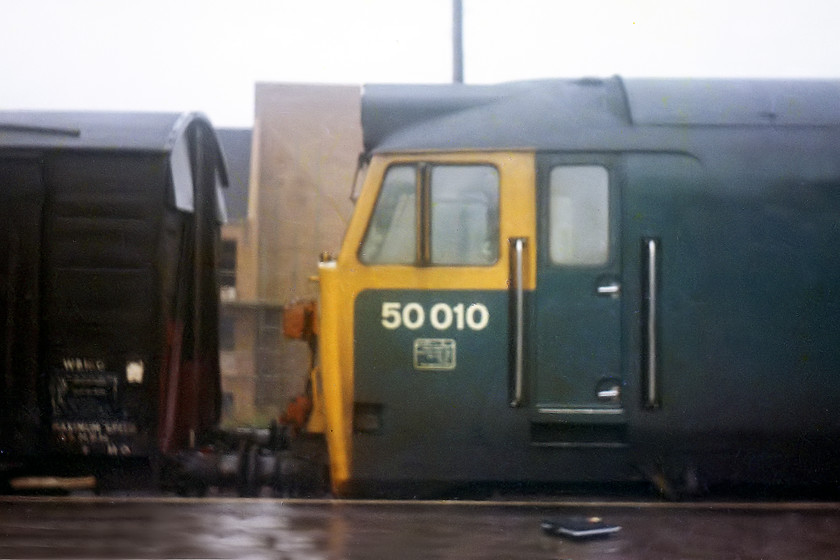 50010, up freight working, Swindon station 
 50010 stands at Swindon leading a freight heading east. I wonder where the 4-wheel vintage wooden bodied van is now....scrapped no doubt but these are the type that you occasionally see sitting in the corner of a farmer's field acting as a store of some kind. Notice my ITT radio-cassette recorder on the platform attempting to capture the sound of the 50 leaving the station. 
 Keywords: 50010 Swindon