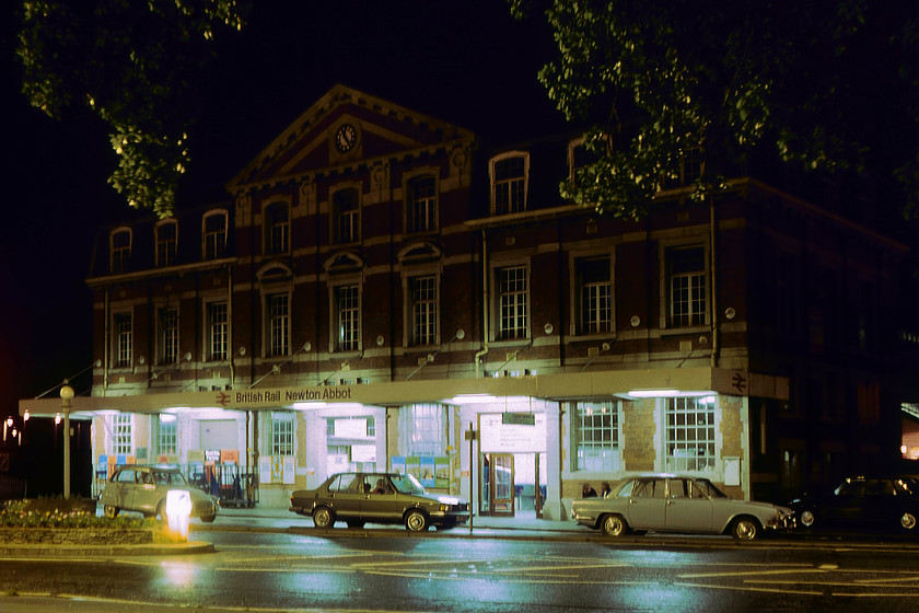 Frontage, Newton Abbot station 
 Dating from the mid-1920s the frontage of Newton Abbot station is seen in the darkness of a Saturday night. The rather crudely applied BR era canopy does not do a great deal for the aesthetics of the otherwise attractive building. The three cars parked in the foreground date the photograph: to the left a Citron Dyane, then a Mk.1 VW Jetta that will be less than a year old and a much older Triumph 2000 Mk.I. 
 Keywords: Frontage Newton Abbot station