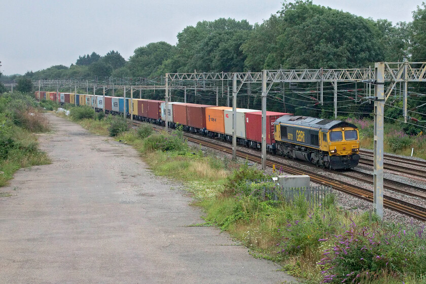 66701, 03.10 Felixstowe North-Trafford Park (4M18, 6E), site of Roade station 
 GBRf's 66701 leads the 4M18 03.10 Felixstowe to Trafford Park heavily loaded Freightliner service past the sight of Roade station. Considering that it is the beginning of August it is an incredibly dull and grey morning with the camera struggling and having to operate at an ISO of 3200, something more akin to taking photographs in January! 
 Keywords: 66701 03.10 Felixstowe North-Trafford Park 4M18 site of Roade station GBRf