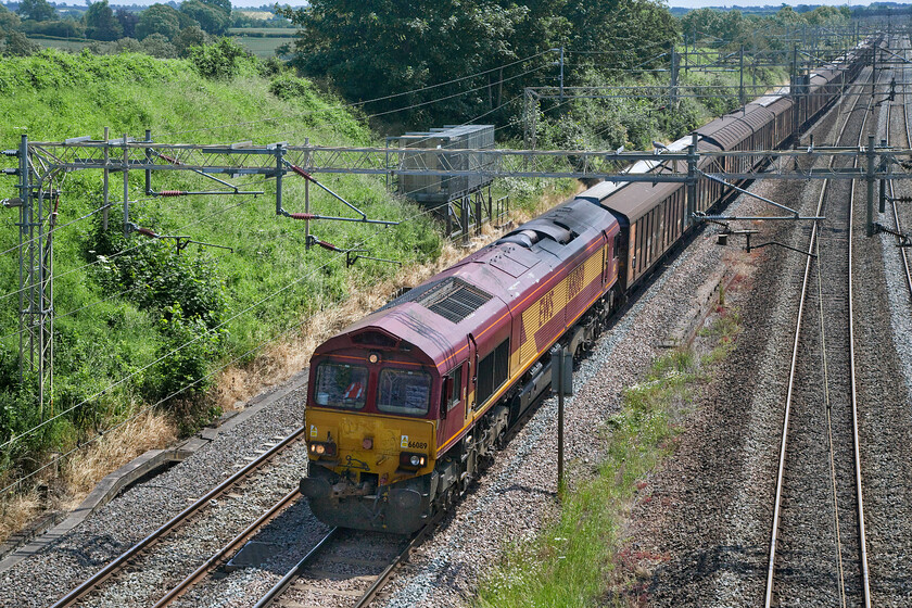 66089, 11.38 Wembley-DIRFT (6M45, 45L), Victoria bridge 
 The regular as clockwork 6M45 bottled water train approaches journey's end at Victoria bridge just south of Roade in Northamptonshire. On this sunny Saturday afternoon and in tricky lighting 66089 leads the 11.38 Dollands Moor to DIRFT (Daventry) train composed of its customary rake of European Cargo Wagons. 
 Keywords: 66089 11.38 Wembley-DIRFT 6M45 Victoria bridge EWS