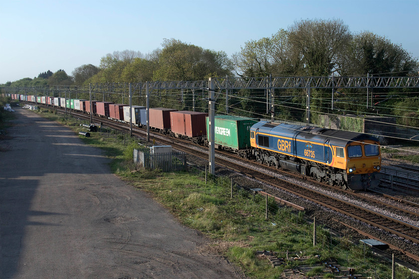 66735, 03.10 Felixstowe North-Trafford Park (4M21, 27E), site of Roade station 
 A little side-lit but 66735 'Peterborough United' still looks good leading the 4M21 03.10 Felixstowe to Trafford Park Freightliner. The train is seen passing the site of Roade station on the down slow line but, unfortunately, it has not all fitted in view with the tail of the train out of site under Ashton bridge such was its length! 
 Keywords: 66735 03.10 Felixstowe North-Trafford Park 4M21 site of Roade station Freightliner 	Peterborough United