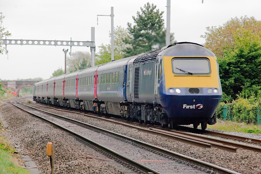 43164, GW 13.15 London Paddington-Cardiff Central (1B37, RT), Steventon Causeway Crossing 
 Power car 43164 leads the 13.15 Paddington to Cardiff Central past Steventon Causeway level crossing. Steventon appeared to have been left 'til last when it came to the installation of the wiring for the incredibly over-budget and late electrification programme. Notice the white sighting panel painted on the bridge in the background, there would have been a semaphore bracket signal just in front of this. This signal was the up starter bracket at the platform end of Steventon station that closed in December 1964. 
 Keywords: 43164 1B37 Steventon Causeway Crossing