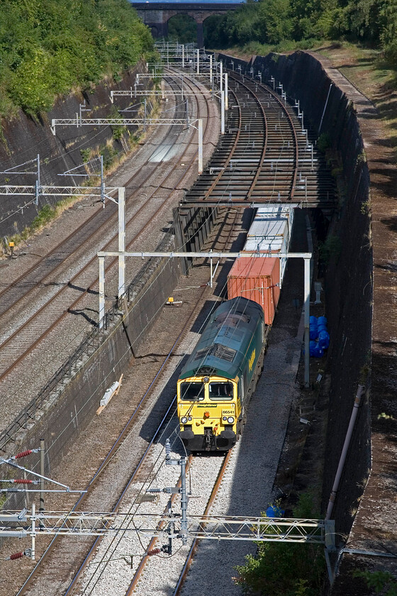 66541, 05.03 Trafford Park-Felixstowe North (4L97), Roade cutting 
 Taken from the lofty heights of a little used occupation bridge above Roade cutting the 4L97 05.03 Trafford Park to Felixstowe Freightliner passes with 66541 slogging away at the front. It is emerging from a section of the slow lines protected by a sturdy framework known locally as the 'birdcage'. This was installed to protect this section of the cutting that has been susceptible to movement and even collapse. 
 Keywords: 66541 05.03 Trafford Park-Felixstowe North 4L97 Roade cutting Freightliner