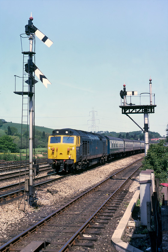 50045, 07.45 Kensington Olympia-St. Austell Motorail (1V34), Exeter Riverside 
 I am not absolutely sure how I managed to get to this spot at Exeter Riverside as by all accounts I should be in somebody's back garden! Either way, it's an unusual spot that sees 50045 'Achilles' approaching Exeter leading a summer Saturday favourite working, the 1V34 Kensington Olympia to St. Austell Motorail service. Whilst the usual rake of Mk.I stock is behind the locomotive, unfortunately, the car flats are out of view at the back of the train. I always liked including these in photographs as the cars added some extra period interest. 
 Keywords: 50045 07.45 Kensington Olympia-St. Austell Motorail 1V34 Exeter Riverside 'Achilles'