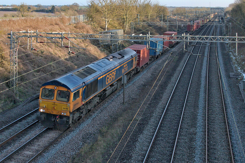 66760, 12.18 London Gateway-Hams Hall (4M47, 51L), Victoria bridge 
 66760 'David Gordon Harris' leads the 4M47 12.18 London Gateway to Hams Hall Freightliner service. The recent bitter winter weather and strong easterly wind made the activity of standing around and waiting for a train not particularly pleasurable at an exposed spot like this one at Victoria bridge just south of Roade. It also took its toll on the efficiency of the camera's batteries with them struggling to hold charge unless I removed them and put them in my pocket!

Coincidentally, I photographed the same Class 66 at this location on a very different type of day back in the last spring. Like then, just as now, we were still under strict COVID restrictions with me out on my local and permitted bout of exercise, see..... https://www.ontheupfast.com/p/21936chg/28991218404/x66760-10-36-felixstowe-north-hams 
 Keywords: 66760 12.18 London Gateway-Hams Hall 4M47 Victoria bridge GBRf David Gordon Harris