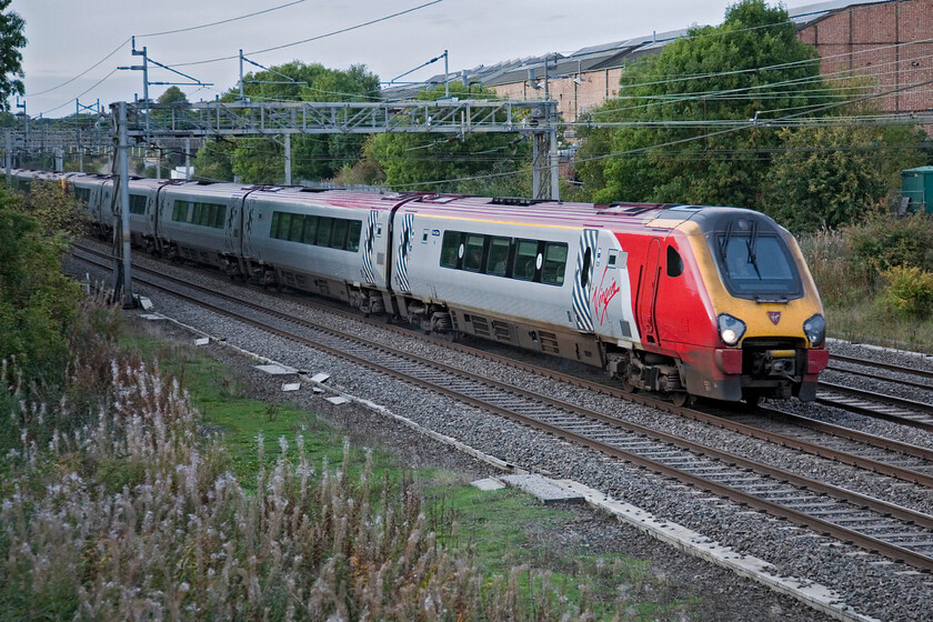 221101 & 221110, VT 13.58 Holyhead-London Euston, Roade 
 221101 'Louis Bleriot' and 221110 'James Cook' pass Roade working the 13.58 Holyhead to London Euston Virgin West Coast service. I am standing in a hard-to-get-to spot atop an embankment where the former Stratford-upon-Avon and Midland Junction Railway (SMJR) used to cross the West Coast line on what was known, colloquially, as the Tin Bridge. 
 Keywords: 221101 221110 13.58 Holyhead-London Euston Roade Voyager Virgin West Coast Louis Bleriot