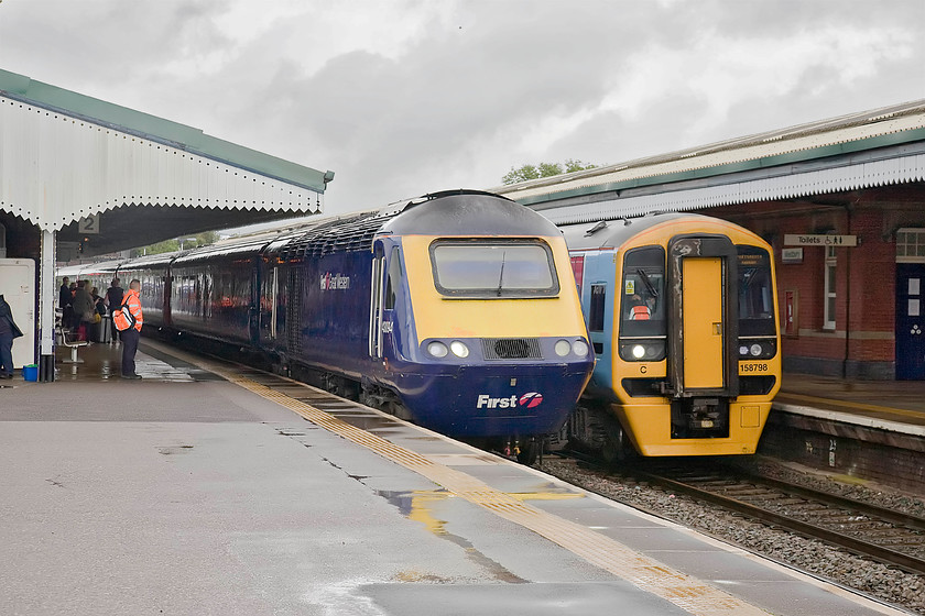 43094, GW 11.33 London Paddington-Exeter St. David`s (1C81) & 158798, GW 11.30 Cardiff Central-Portsmouth Harbour (1F13), Westbury station 
 After the torrential rain from earlier, it has begun to brighten up a bit at Westbury station. HST power car 43094 brings up the rear of the 11.33 Paddington to Exeter service whilst 158798 has just arrived forming the 11.30 Cardiff Central to Portsmouth Harbour train. Note that both trains left within three minutes of each other and that they both arrive at Westbury together with the former having covered ninety-five miles but the latter a mere sixty-five. 
 Keywords: 43094 11.33 London Paddington-Exeter St. David`s 1C81 158798 11.30 Cardiff Central-Portsmouth Harbour 1F13 Westbury station First Great Western HST Sprinter