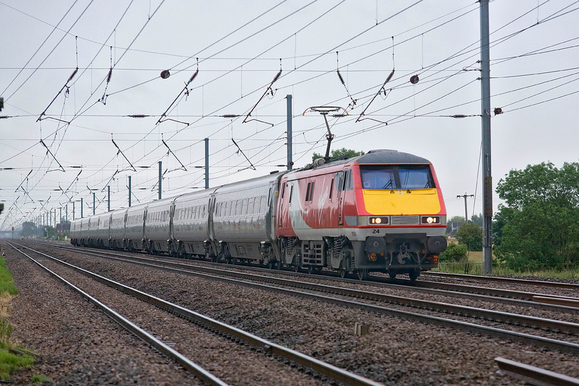 91124, GR 08.30 London King`s Cross-Newcastle (1N08), Holme Green crossing TL192426 
 At full chat on the ECML, 91124 powers the 08.30 King's Cross to Newcastle past Holme Green crossing in Bedfordshire. This image clearly shows the height and extension of the pantograph as fitted to the Class 91s. The design of this and the 'budget' electrification constructed by BR in the 1980s is often the cause of failure with wires getting tangled in the pantographs and tearing down long stretches of it. 
 Keywords: 91124 08.30 London King`s Cross-Newcastle 1N08 Holme Green crossing TL192426 IC225 Virgin East Coast