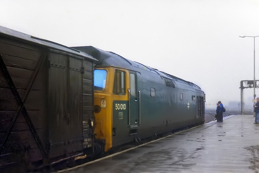 50010, up freight working, Swindon station 
 Some spotters gather around 50010 at Swindon. Unusually, it is leading a freight working heading east. Note the vintage wooden bodied 4-wheel van behind the engine. It will soon head off into the gloom of this December day. 
 Keywords: 50010 Swindon