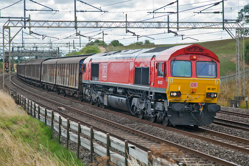 66027, 09.26 Dollands Moor-DIRFT (6M45), Old Linslade 
 66027 looks really smart in it new DB livery as it passes Old Linslade. The 66 is leading the daily 09.26 Dollands Moor to the Daventry railfreight terminal. This working comprises a long set of cargo wagons full of bottled water that originated in Europe. This then goes on for distribution throughout the country to to satisfy our insatiable appetite for plastic bottles full of expensive 'mineral' water. The empty wagons return later in the evening ready for next day's delivery. 
 Keywords: 66027 6M45 Old Linslade