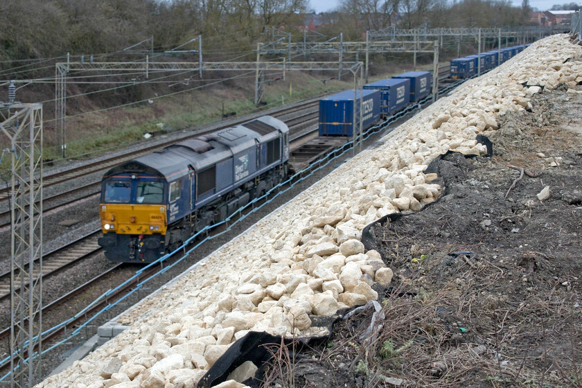 66424, 13.09 DIRFT-Tilbury (4L48, RT), Ashton Road bridge 
 With the recent embankment work in sharp focus and the subject slightly blurred, this is the new scene at Ashton Road bridge between the villages of Roade and Ashton in Northamptonshire. In the background, 66424 again hauls the 4L48 13.09 Daventry to Tilbury 'Tesco Express'. I have many pictures of this DRS liveried Class 66 with the majority of them showing it hauling this particular working! 
 Keywords: 66424 13.09 DIRFT-Tilbury 4L48 Ashton Road bridge