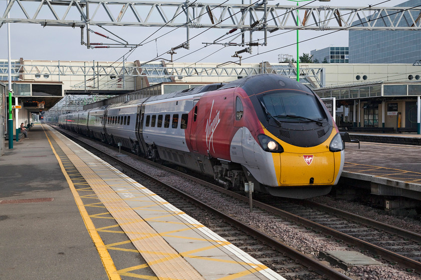 390043, VT 06.10 Manchester Piccadilly-London Euston (1A05, 3E), Milton Keynes Central station 
 390043, presently un-named, passes through Milton Keynes station at full line speed with the 06.10 Manchester Piccadilly to London Euston. A shutter speed of 1/2000 sec. has been used to capture this image but at very close examination in Photoshop there is still the very slightest hint of motion blur in, for example, the Virgin badge on the nose cone. 
 Keywords: 390043 1A05 Milton Keynes Central station