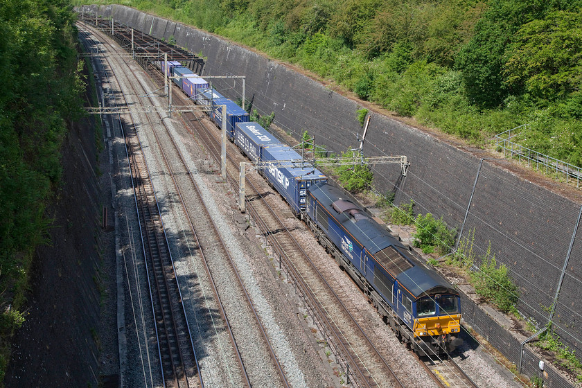 66434, 13.51 DIRFT-Purfleet (4L48, 1E), Roade cutting 
 66434 labours on the steady upgrade from Northampton as it enters Roade cutting leading the daily 4L48 13.51 Daventry to Purfleet Tesco logistics service. It is DRS operated services such as this that have kept us fed during the recent months bringing vast amounts of imported products that we are all used to seeing on the supermarket shelves. 
 Keywords: 66434 13.51 DIRFT-Purfleet 4L48 Roade cutting DRS Direct Rail Services